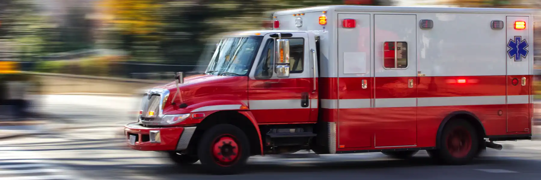 Photo of an red ambulance at a city street. Blurred motion. Urgency. Emergency