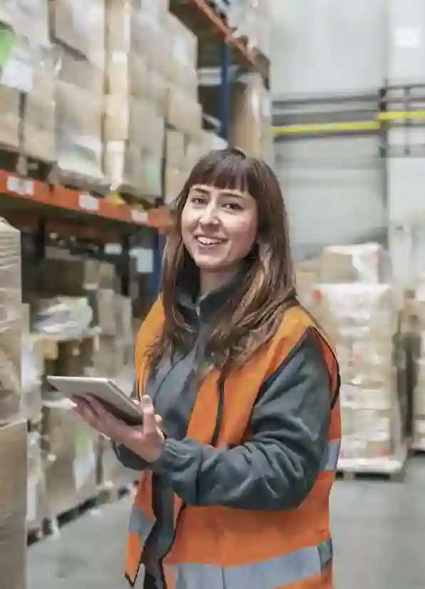 A woman in a vest works in a warehouse